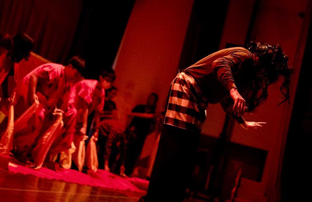 A group of people are dancing on a stage in a dark room.