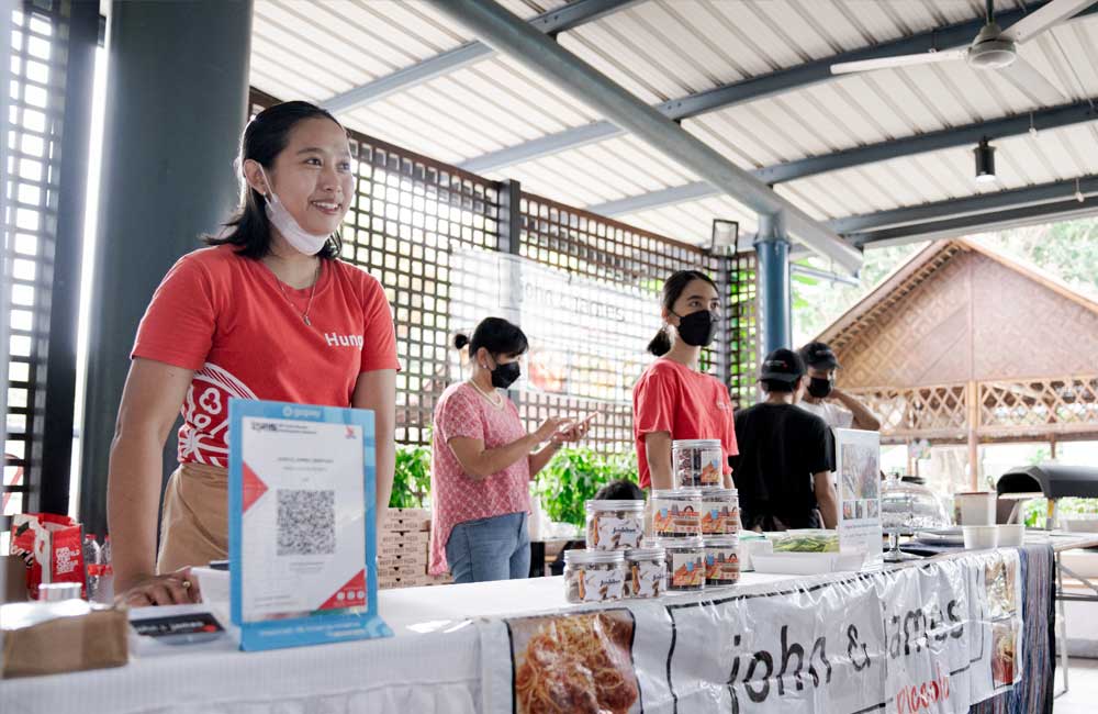 A woman wearing a mask is standing at a counter in a restaurant.