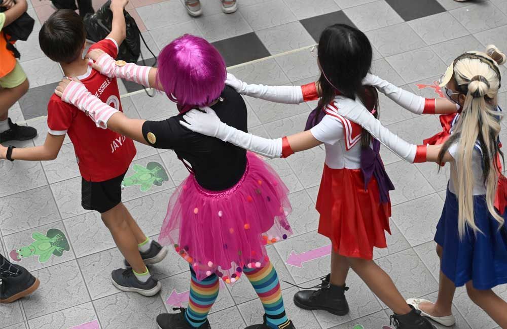 A group of children dressed in costumes are dancing in a circle.