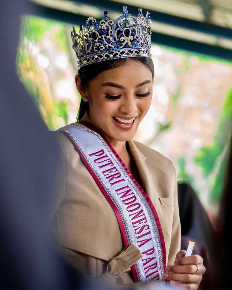 A woman is wearing a crown and a sash that says puteri indonesia party.
