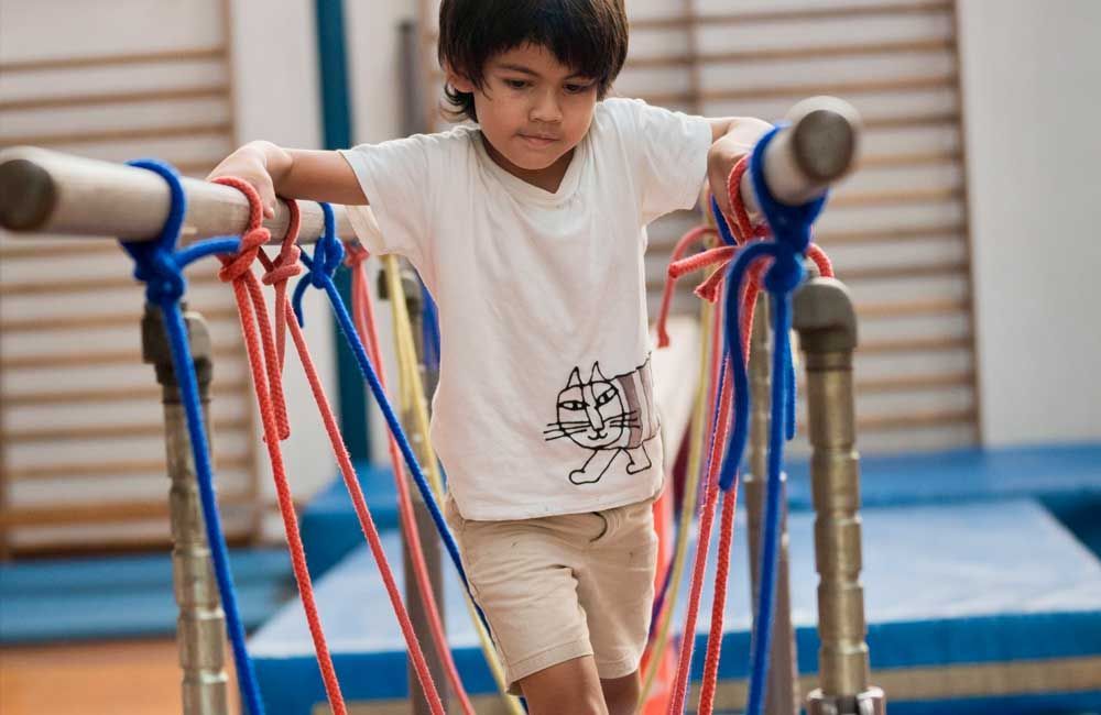 A young boy is playing with ropes in a gym.