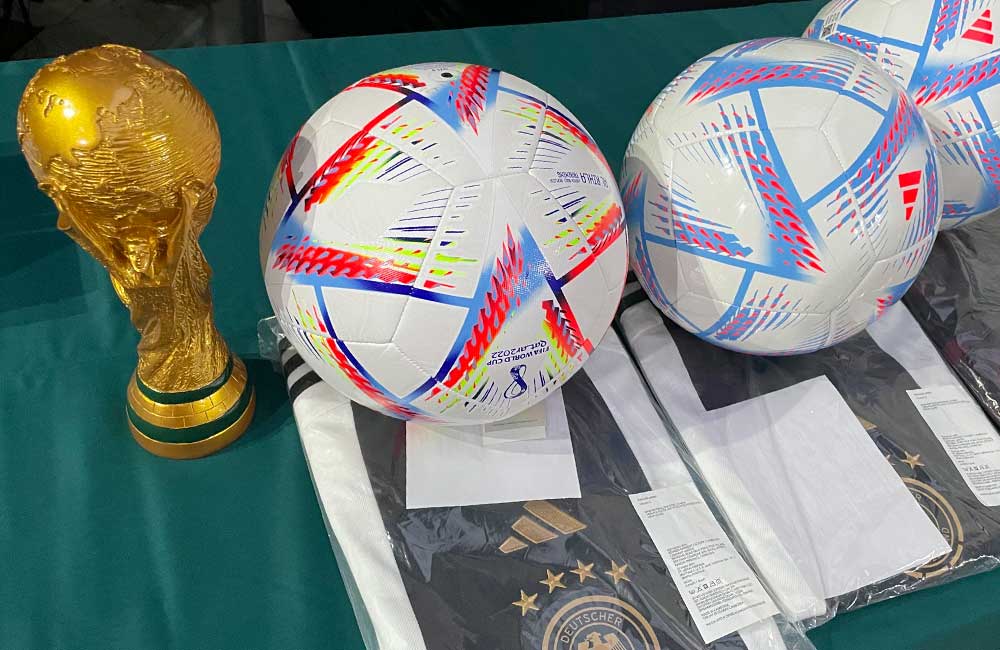 Two soccer balls and a trophy are on a table.
