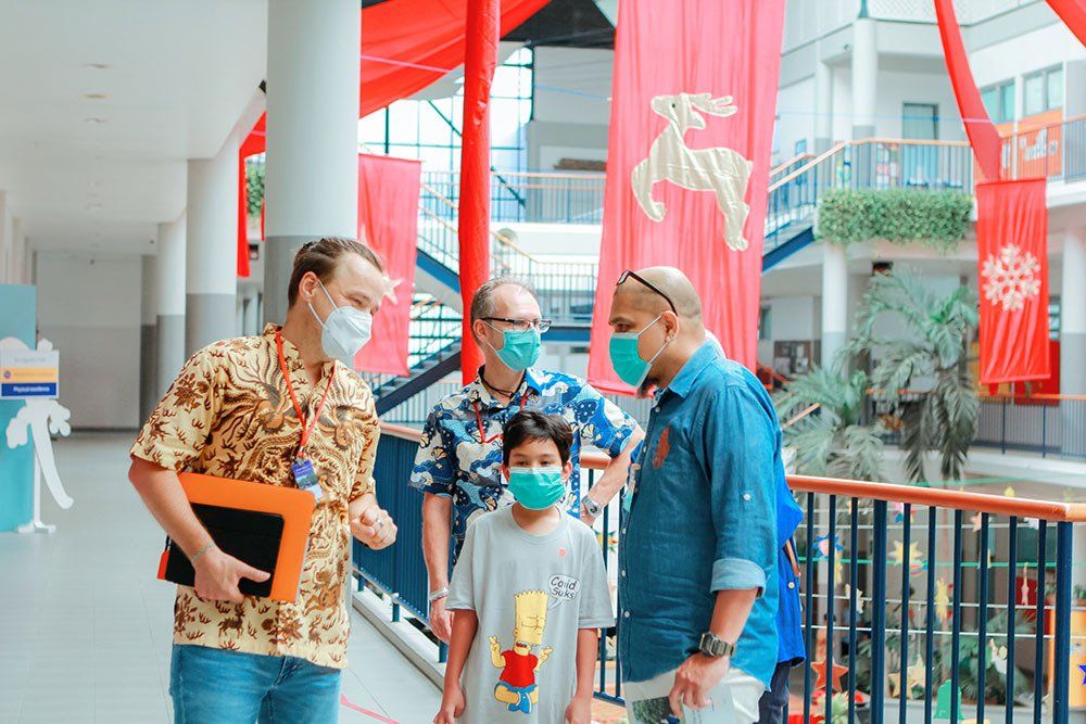 A group of people wearing face masks are standing next to each other in a hallway.