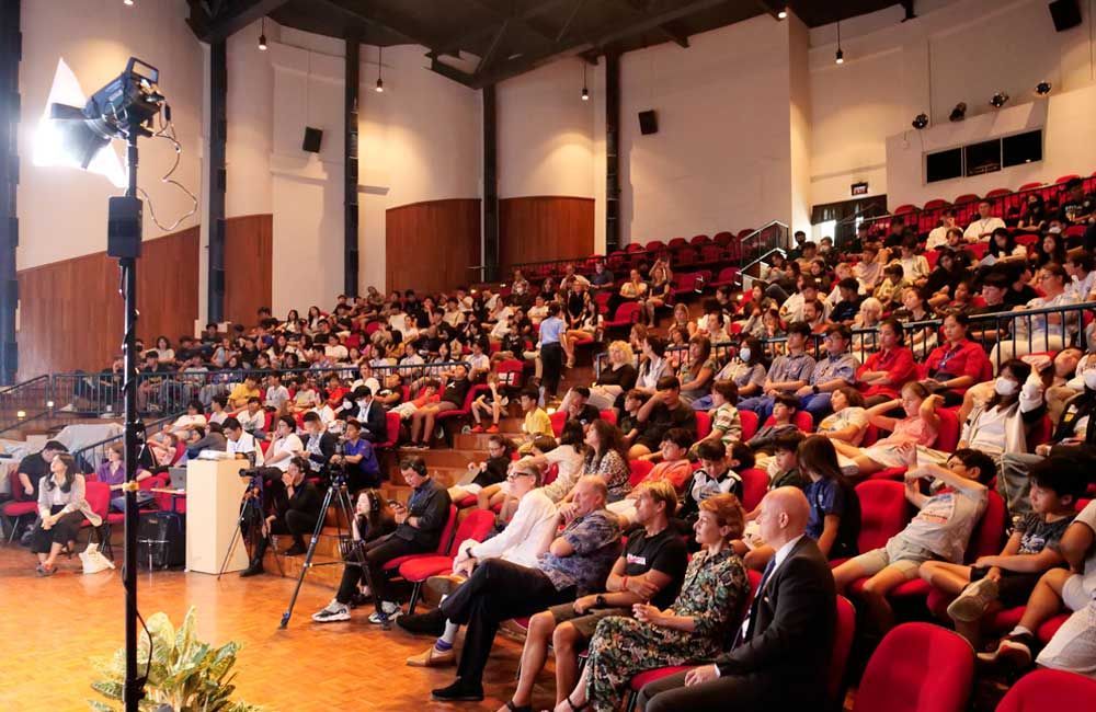 A large group of people are sitting in a large auditorium.