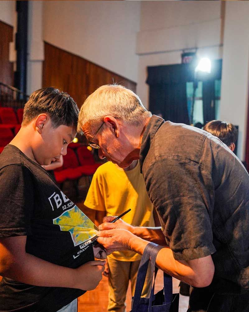 A man is signing a piece of paper for a young boy