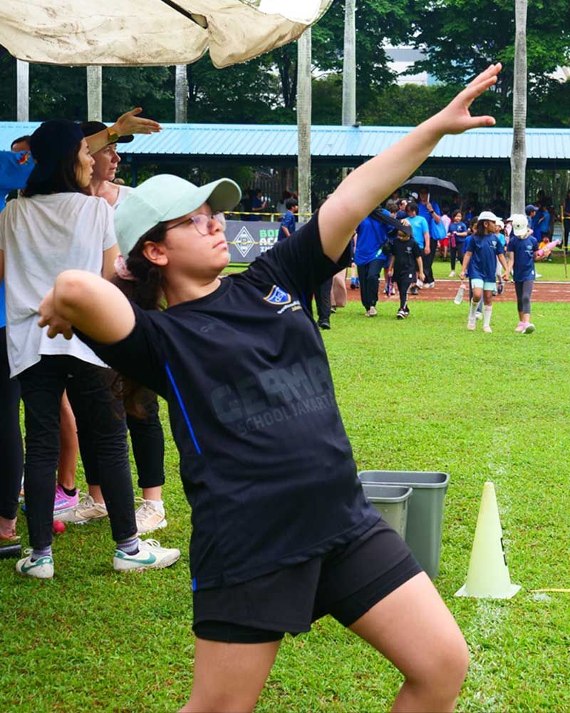 A woman in a black shirt is throwing a ball in a field