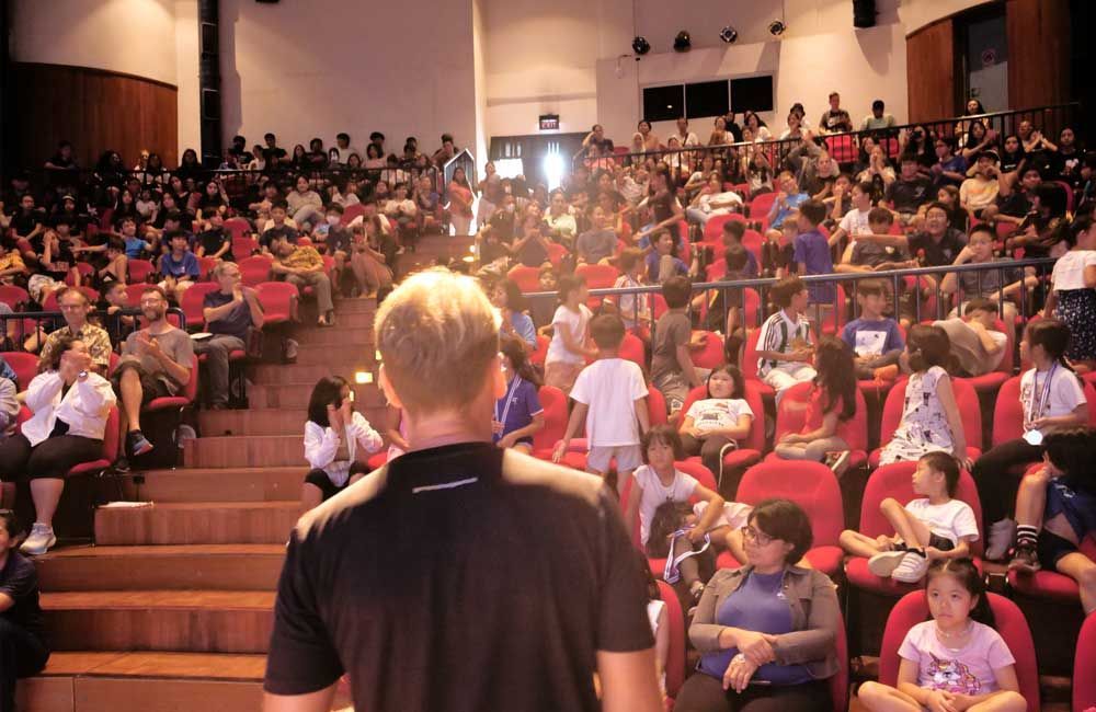 A man is standing in front of a crowd of people in an auditorium.