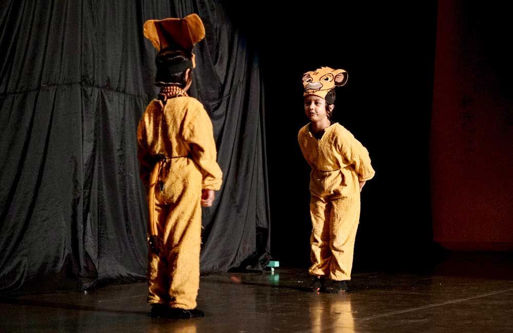 Two children in lion king costumes are standing on a stage.