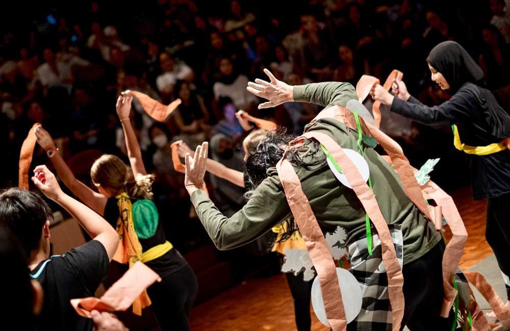 A group of people are dancing on a stage in front of a crowd.