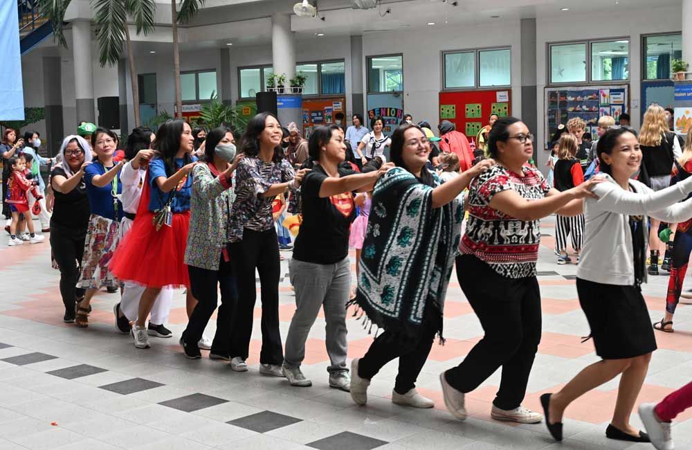 A group of women are dancing in a line in front of a building.
