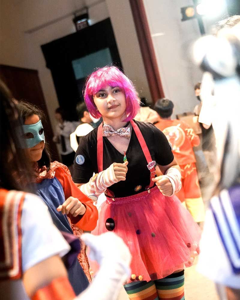 A woman in a pink wig is standing in a crowd of people