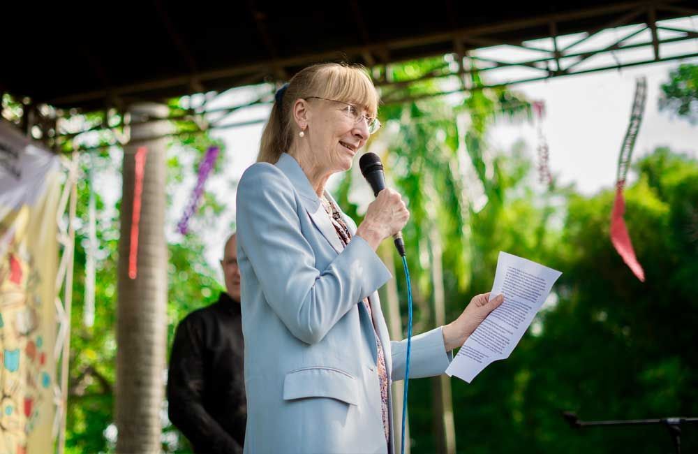 A woman is standing in front of a microphone holding a piece of paper.