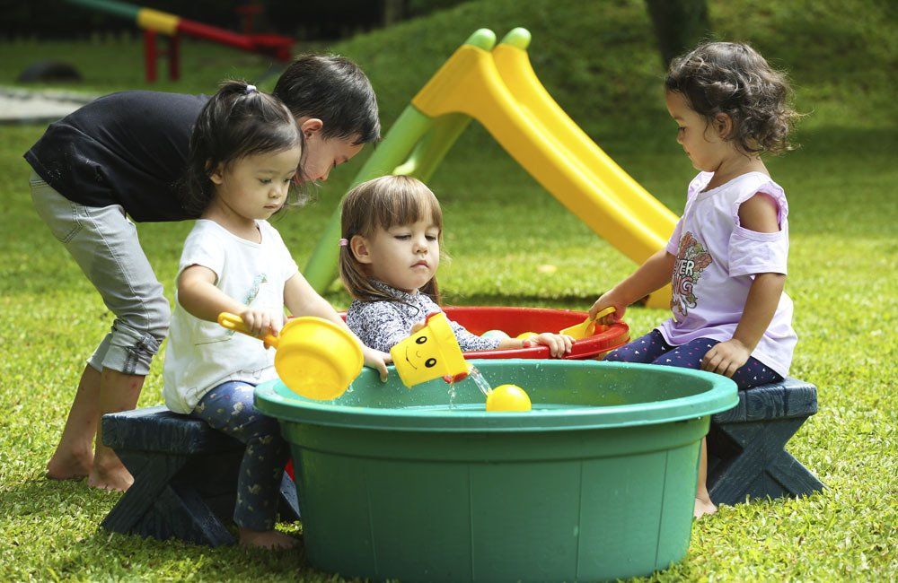 A man and two little girls are playing in a sandbox