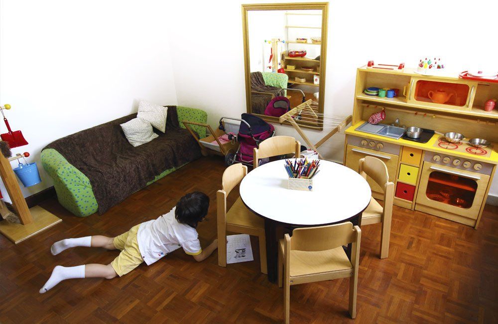 A child is laying on the floor in a room with a table and chairs