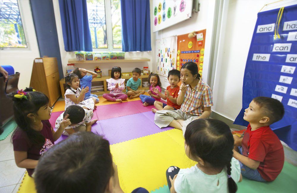A group of children are sitting in a circle on the floor in a classroom