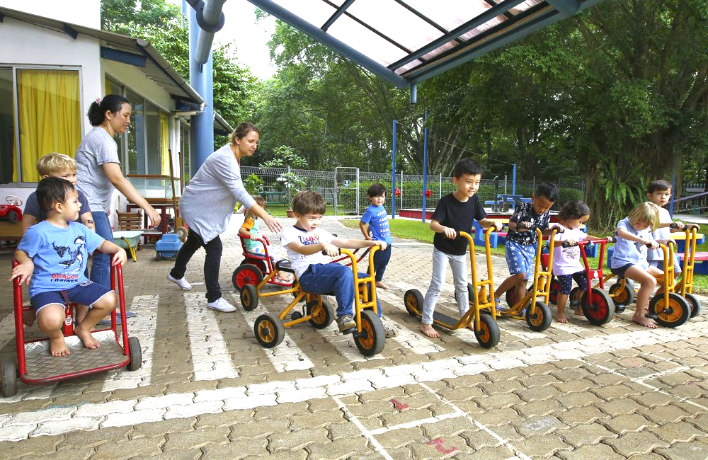 A group of children are riding tricycles in a playground.