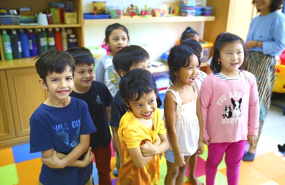 A group of children are standing next to each other in a room.
