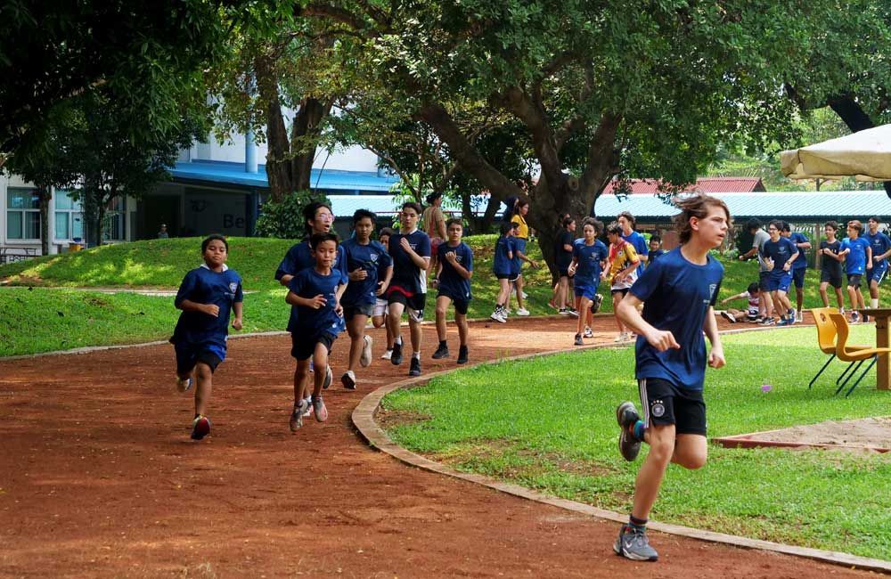 A group of children are running on a track in a park.