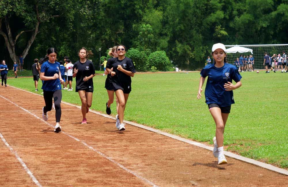 A group of young girls are running on a track.