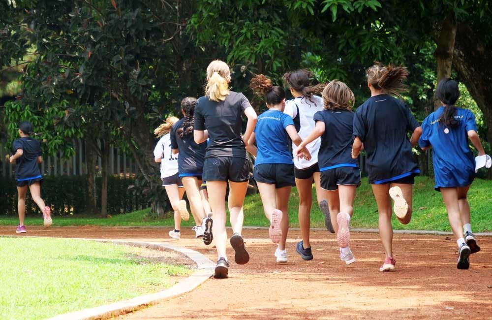 A group of young girls are running on a track.