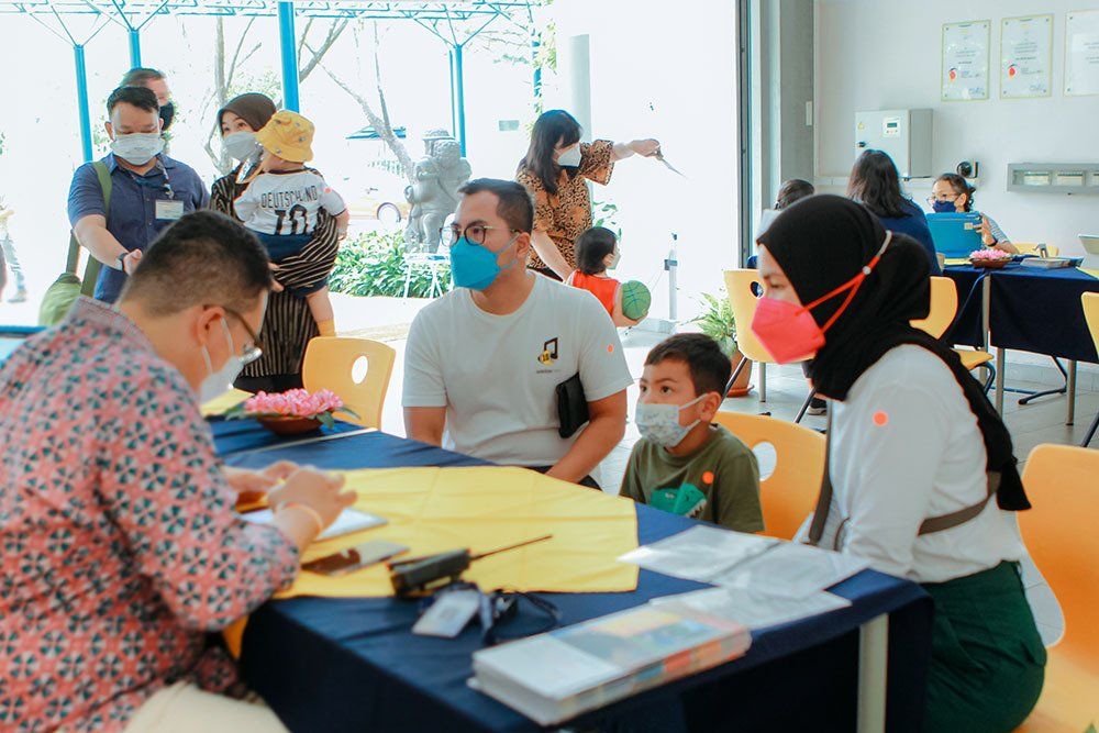 A group of people wearing face masks are sitting around a table.