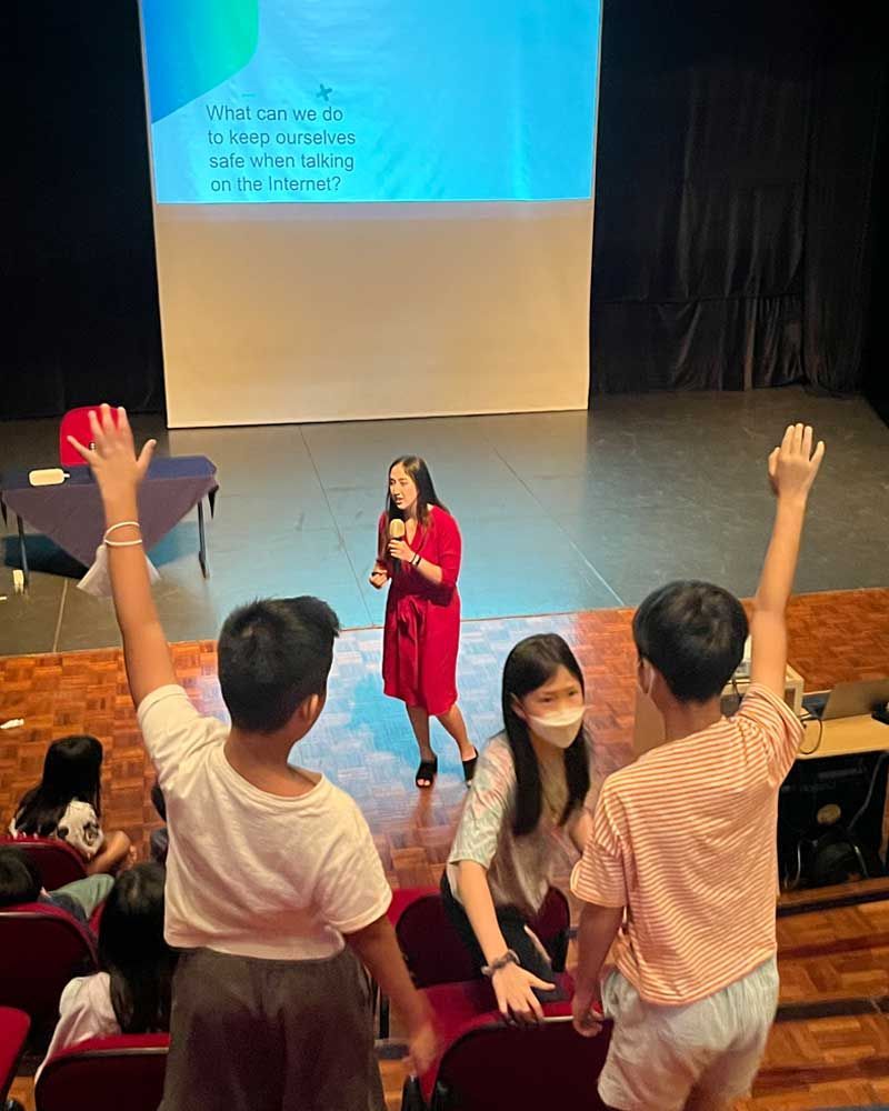 A group of people are raising their hands in front of a projector screen.