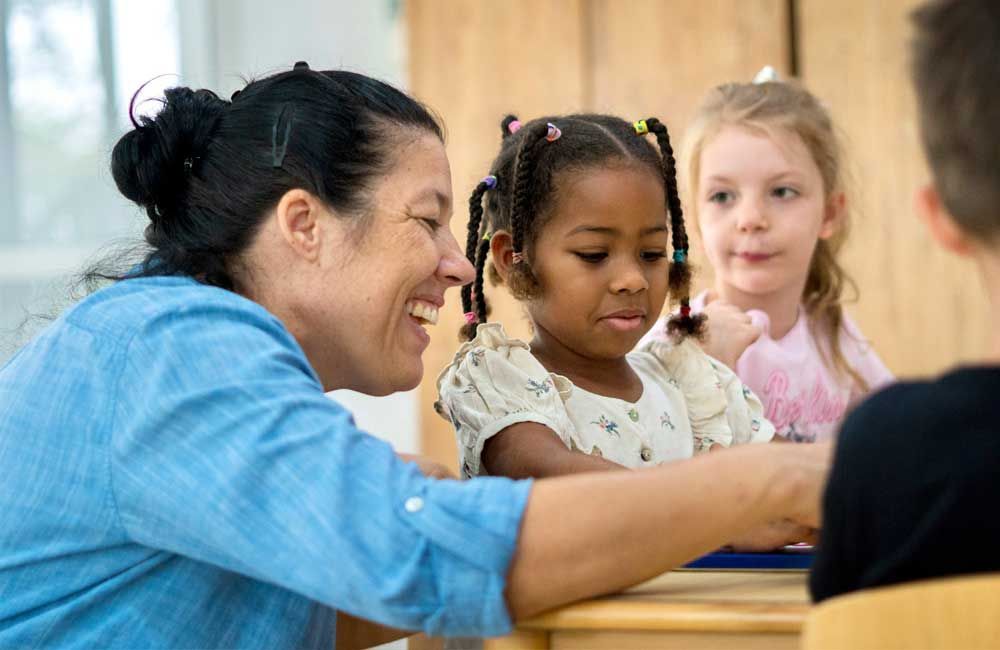 A woman is talking to a little girl in a classroom.