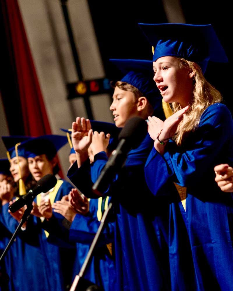 A group of graduates are singing into microphones