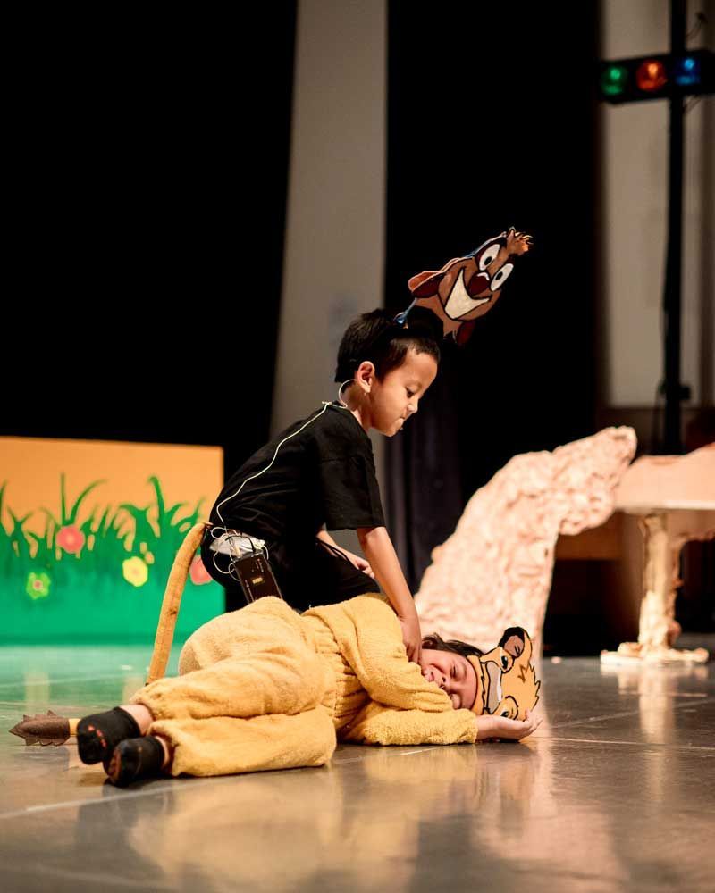 A boy in a tiger costume is laying on the floor next to another boy in a lion costume.