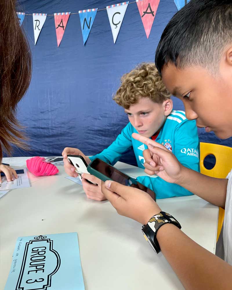 A group of young boys are looking at a cell phone