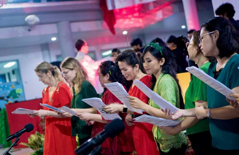 A group of people are singing in a choir in front of microphones.