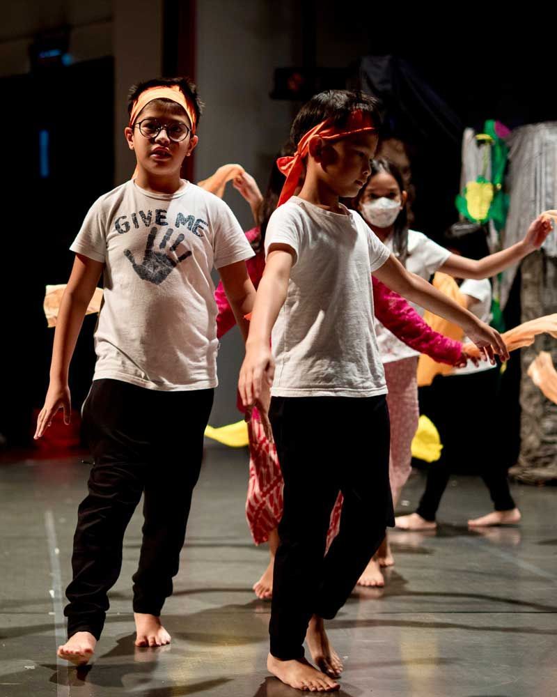 A group of young children are dancing on a stage.