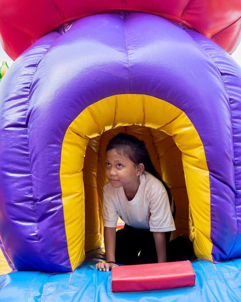 A little girl is crawling through an inflatable tunnel.
