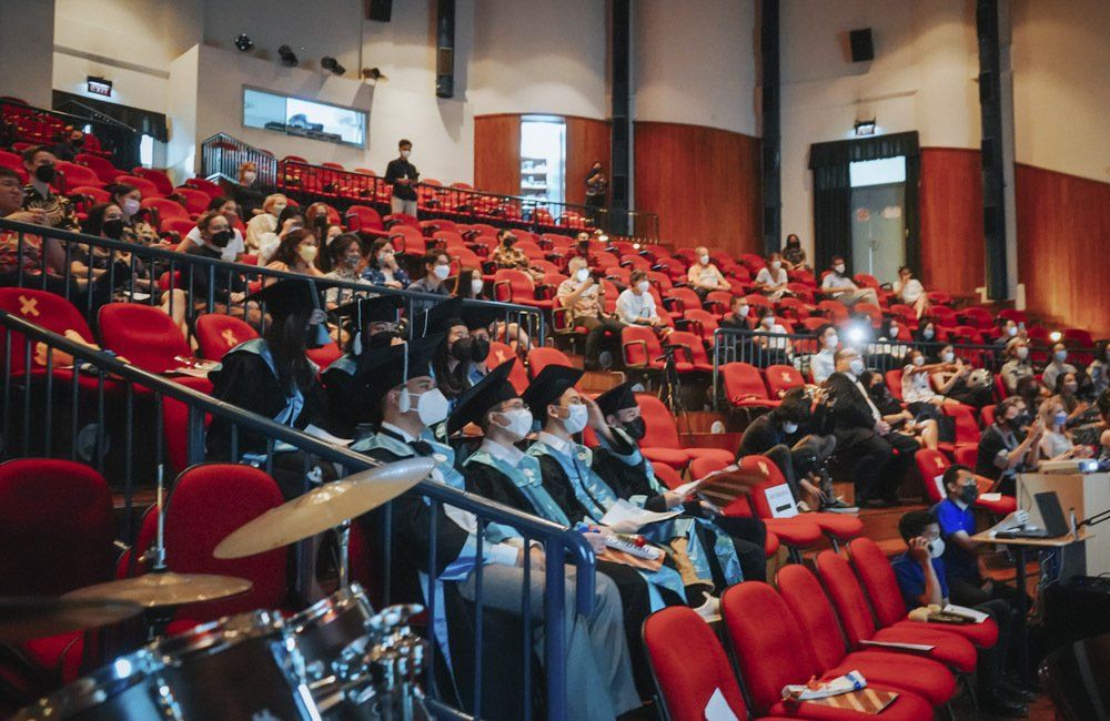 A large group of people are sitting in an auditorium wearing masks.