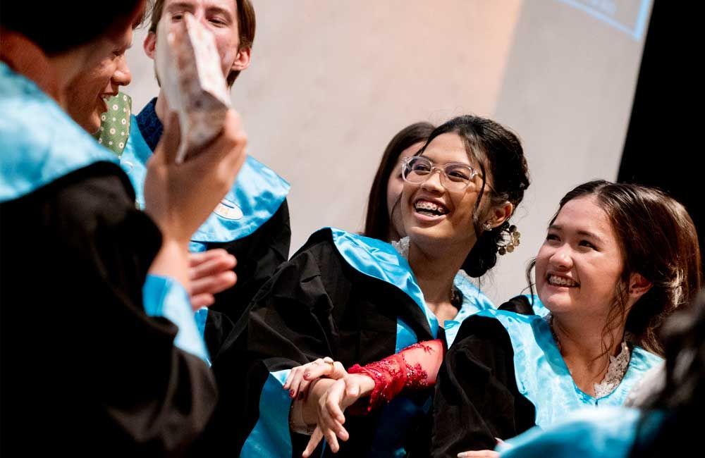 A group of people in graduation gowns are laughing together.
