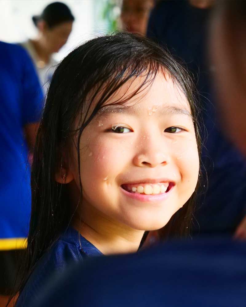A little girl with wet hair is smiling for the camera.