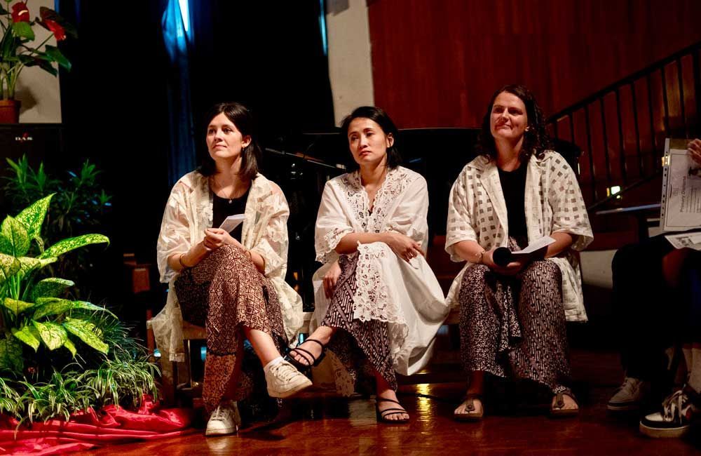Three women are sitting next to each other on a stage.