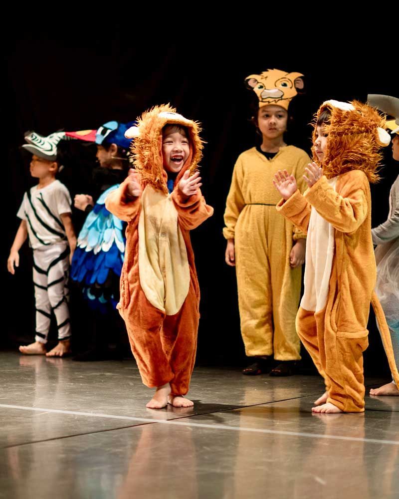 A group of children dressed in animal costumes are standing on a stage.