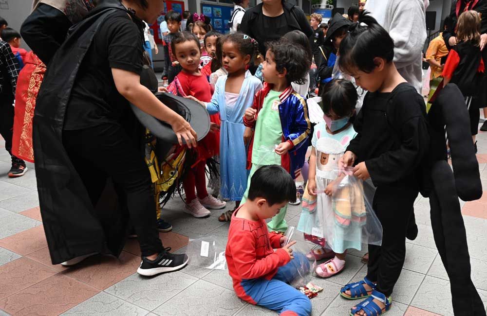 A group of children dressed in costumes are standing on a sidewalk.