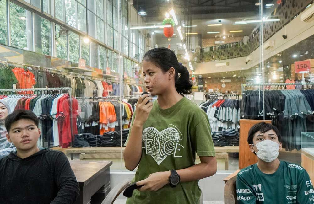 A woman is talking into a microphone in a store.