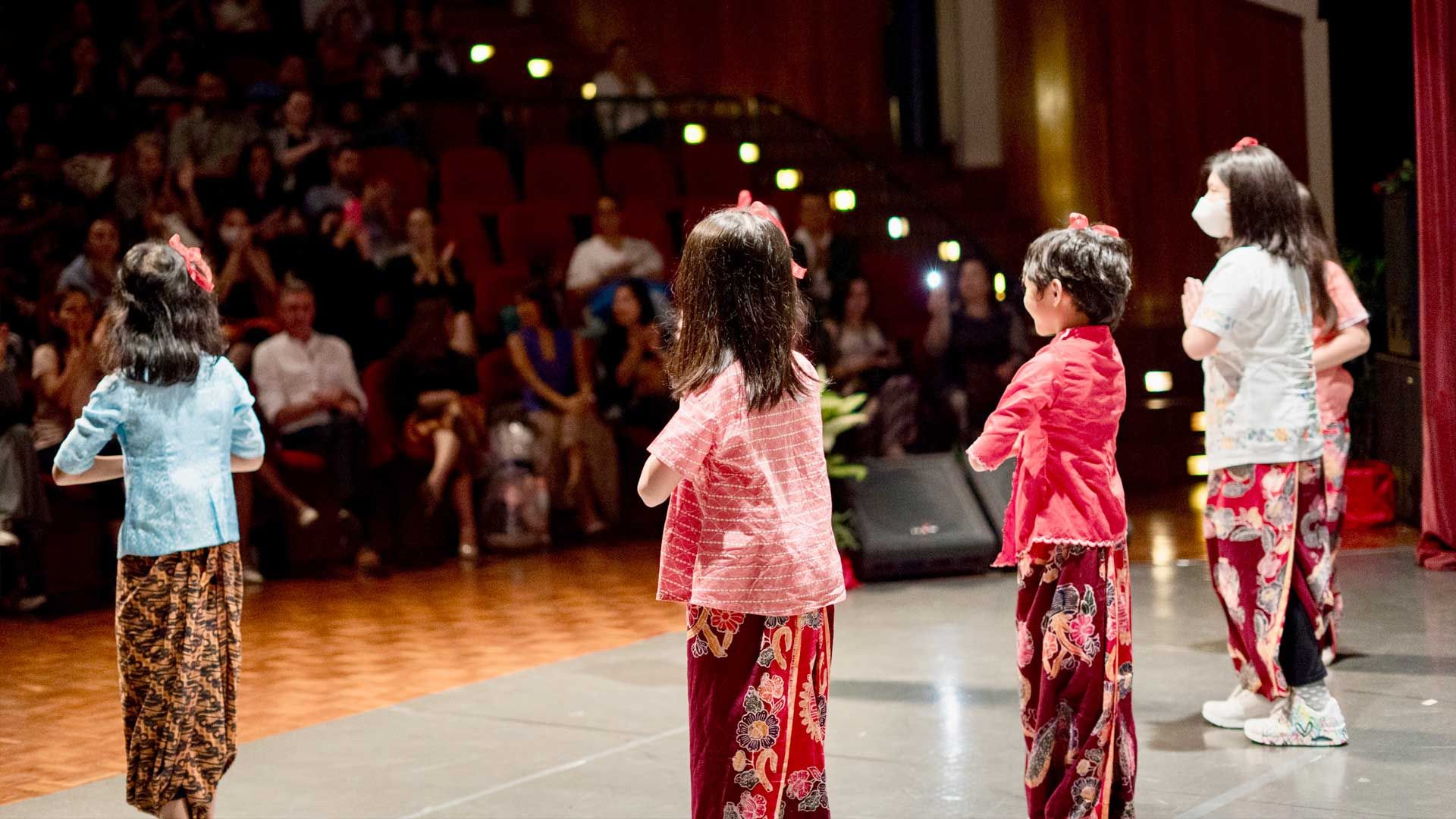 A group of young girls are dancing on a stage in front of a crowd.