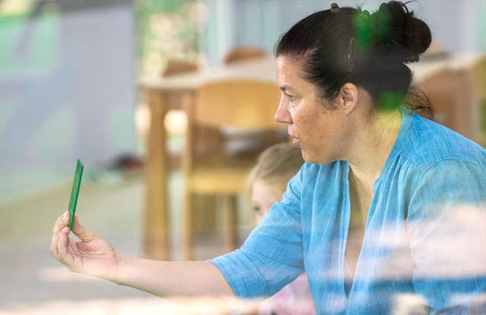 A woman is holding a piece of paper in front of a child.