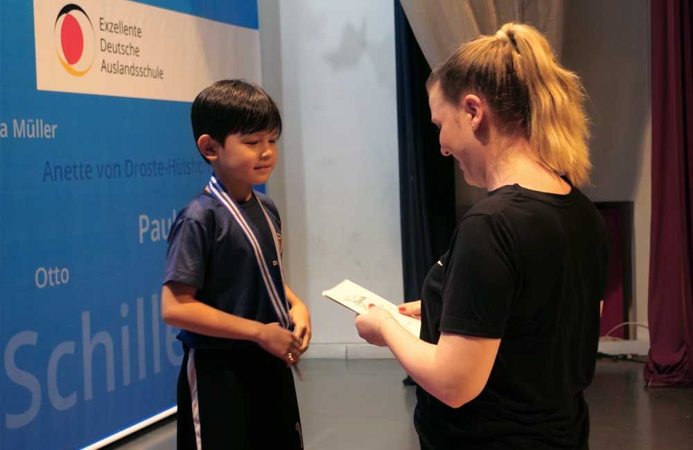 A woman is giving a medal to a young boy