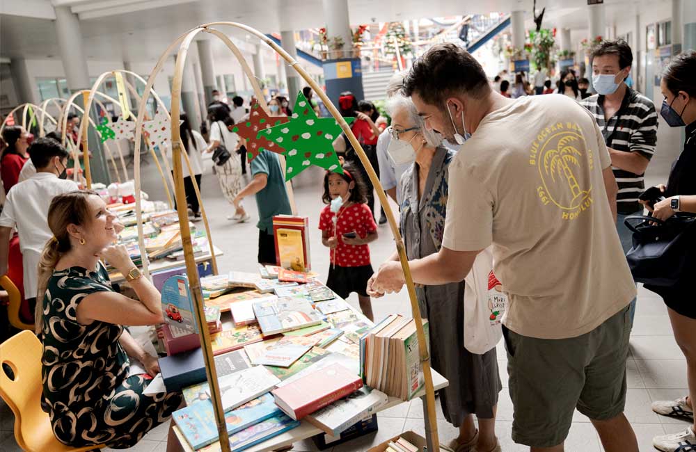 A group of people are standing around a table looking at books.