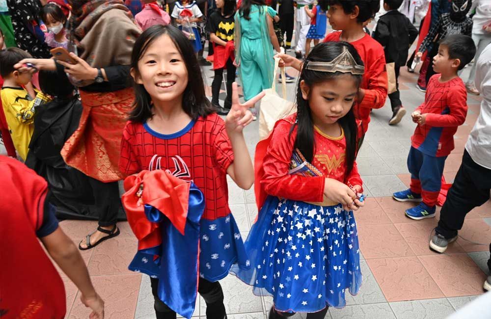 A group of children dressed in costumes are standing on a sidewalk.