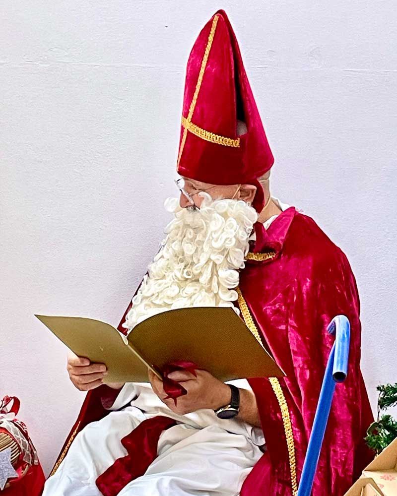 A man dressed as santa claus is reading a book