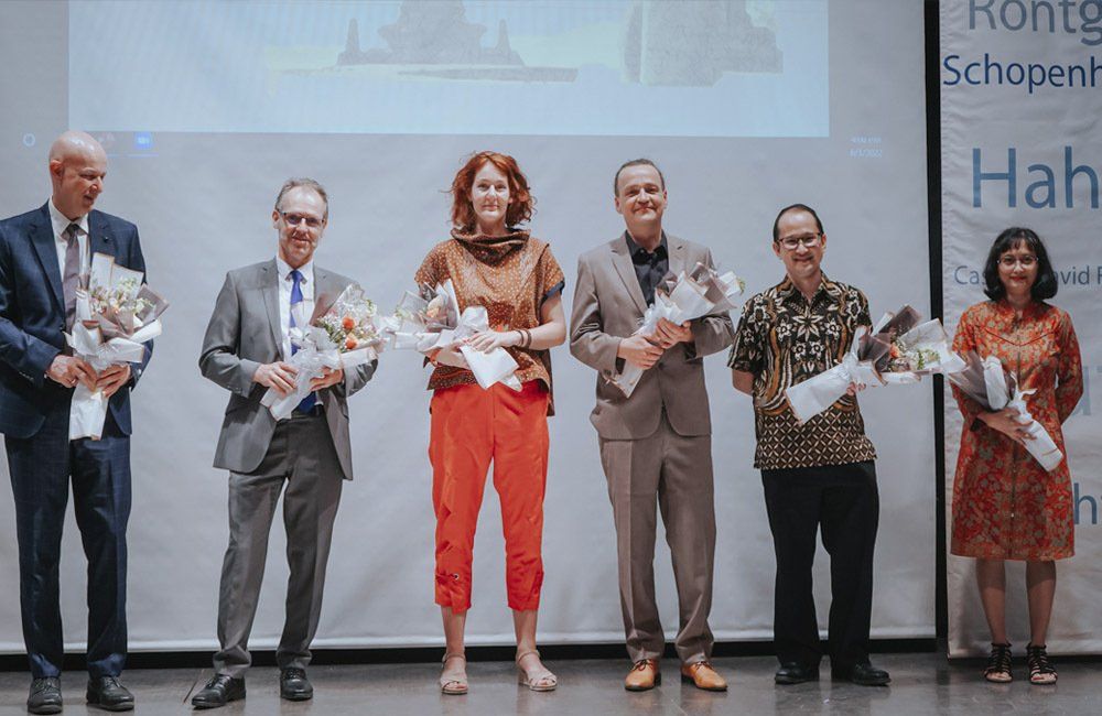 A group of people are standing next to each other on a stage holding flowers.