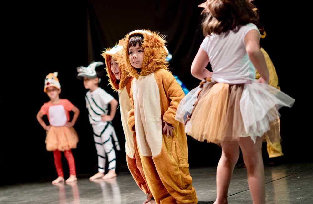 A group of children dressed in animal costumes are standing on a stage.