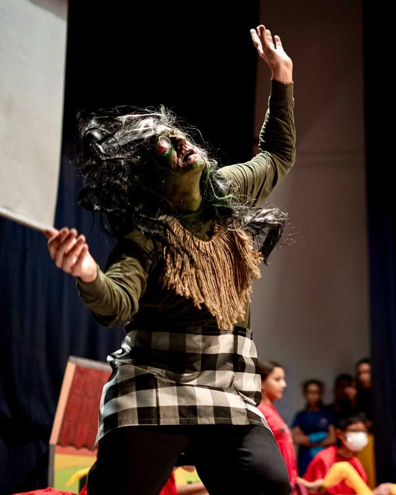 A woman with green paint on her face is holding a sign
