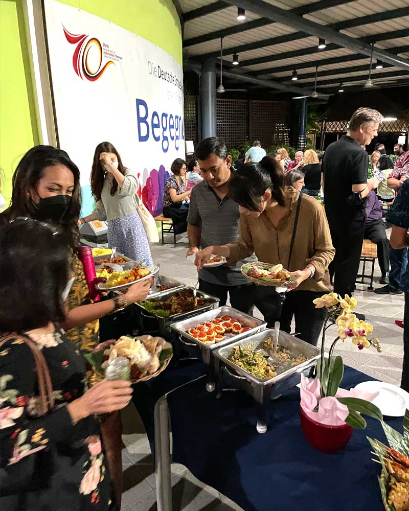 A group of people are standing around a table eating food.